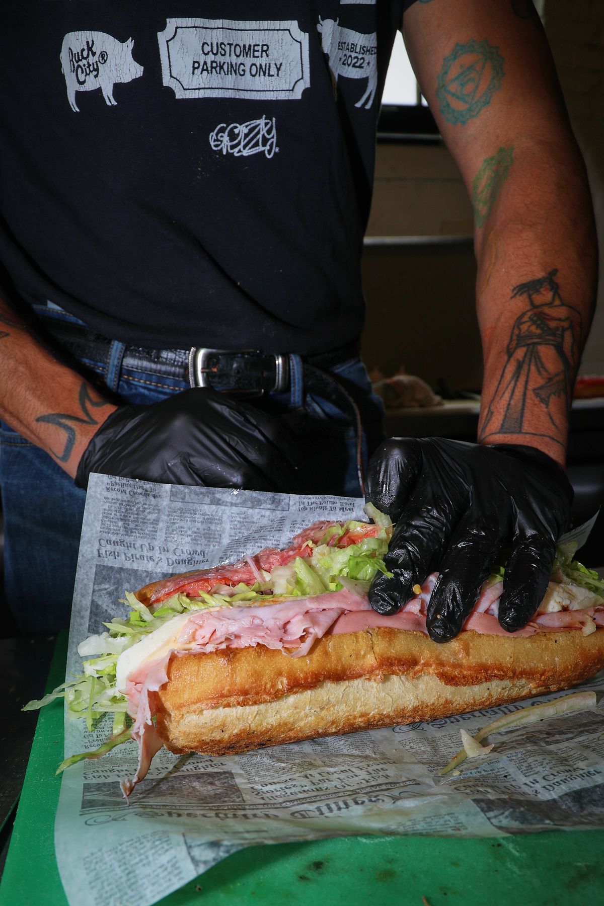 A stacked Italian sub held in gloved hands